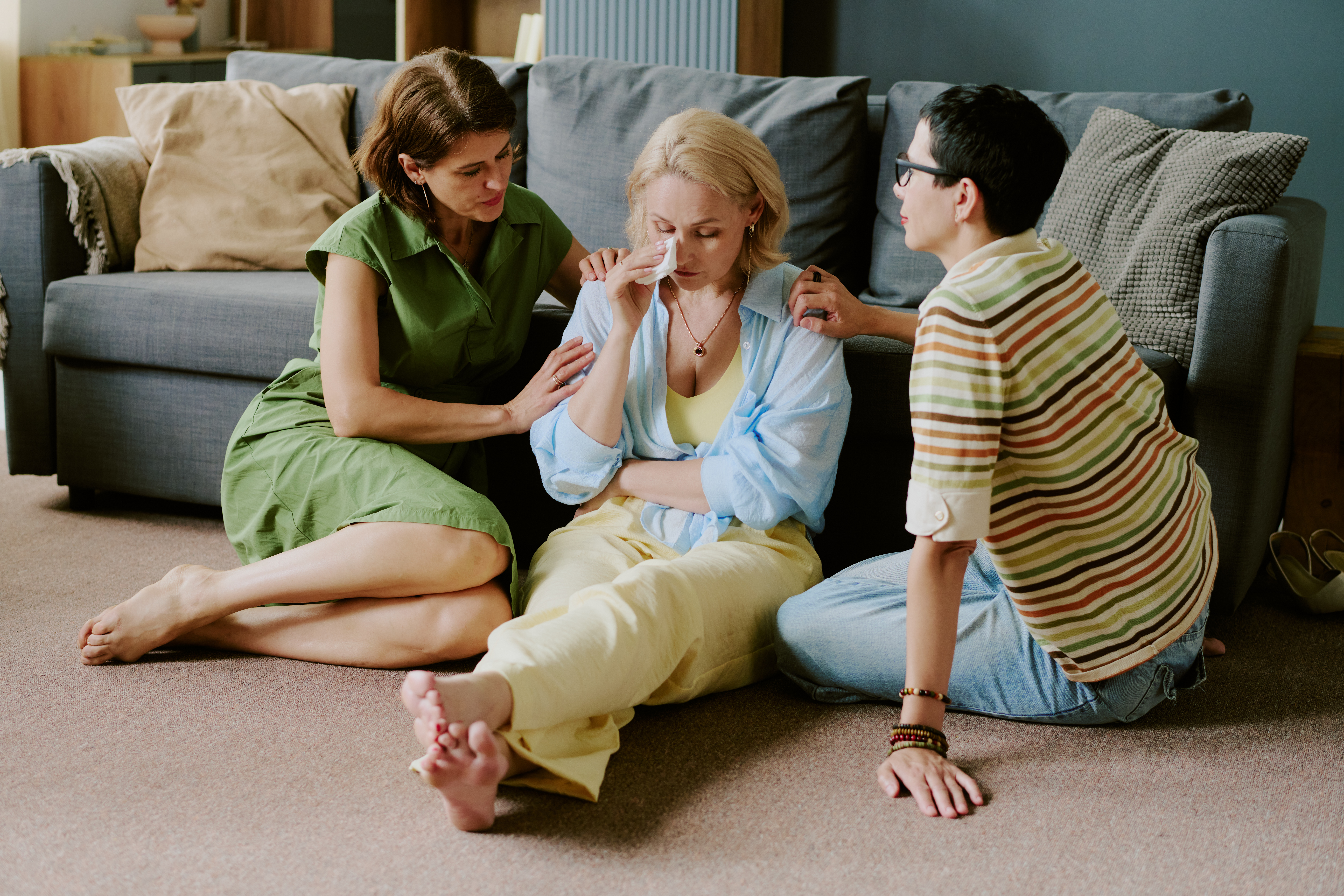Middle Aged Caucasian Woman Comforted by Girlfriends Sitting on Floor