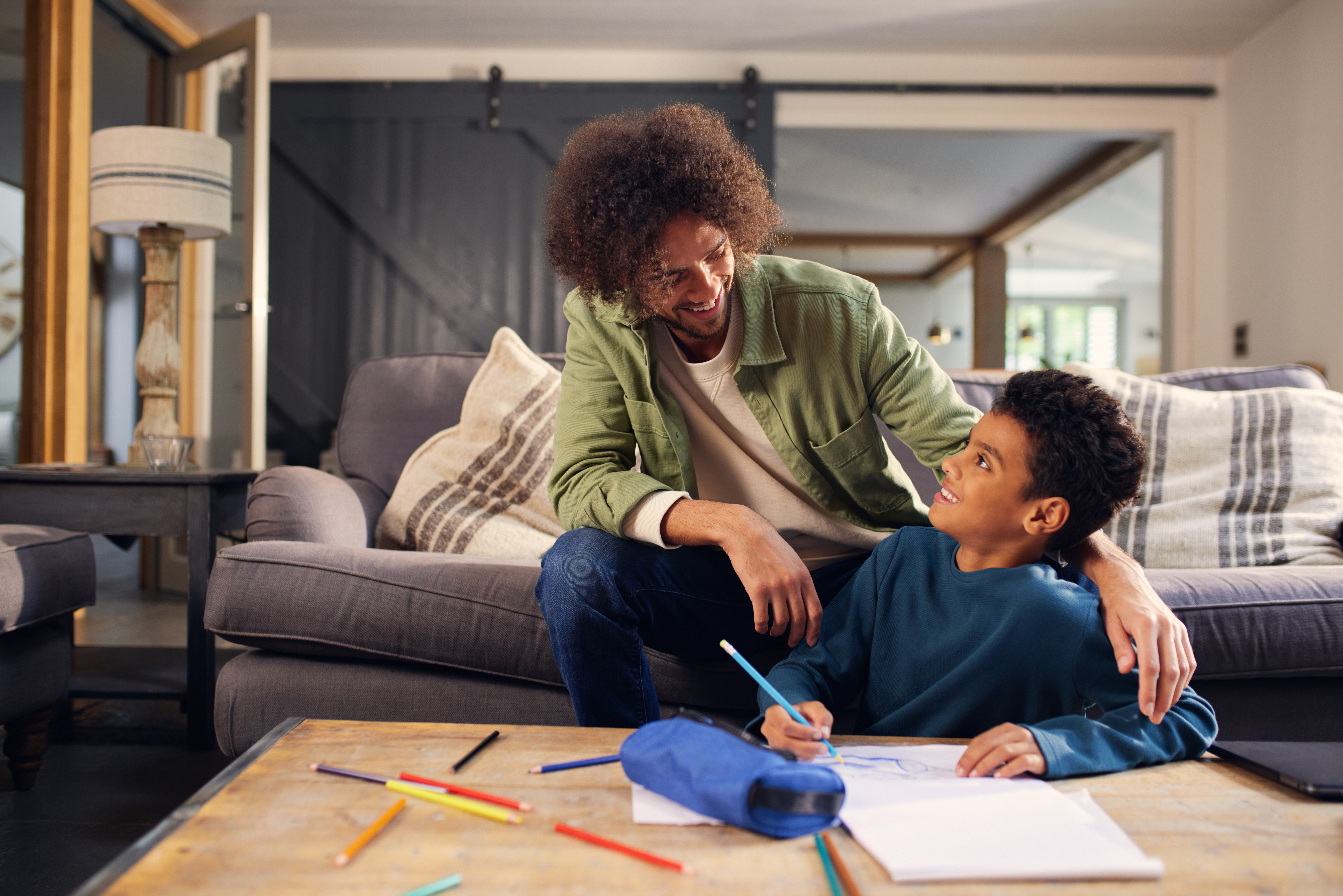 Parent and child drawing together at a table during a custody transition.