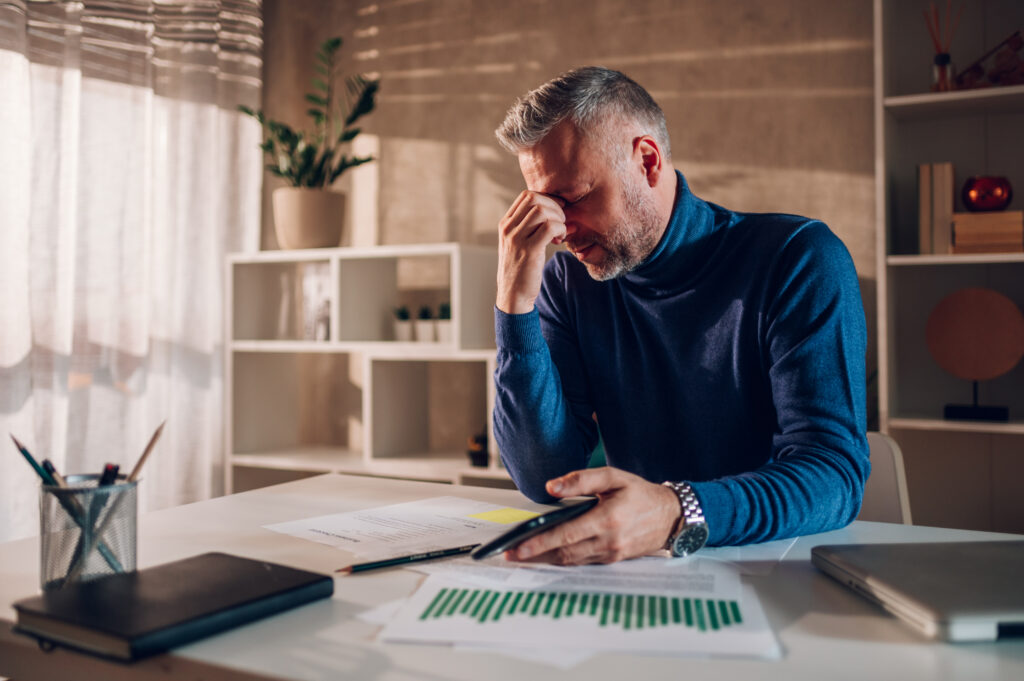 Business owner reviewing financial documents in a living room during divorce planning.