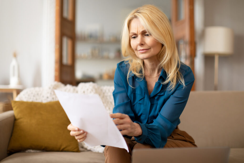 Middle-aged woman reviewing divorce and alimony paperwork at home.